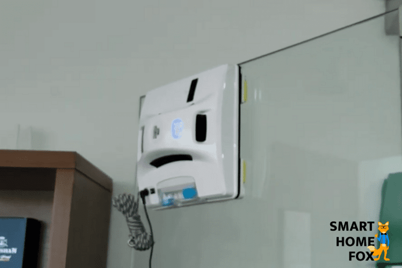 Ein Fensterputzroboter wischt ein rahmenloses Fenster und bleibt vor dem Abgrund stehen